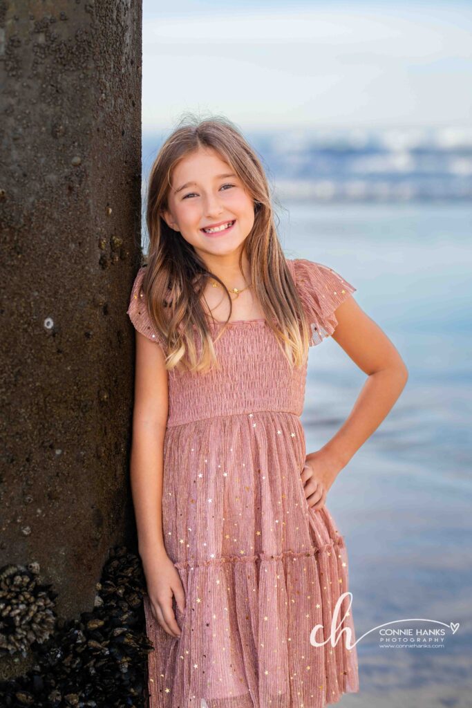 Family photos at Scripps Pier, La Jolla Beach. Stylized family with toes in sand at pier and cliffs.