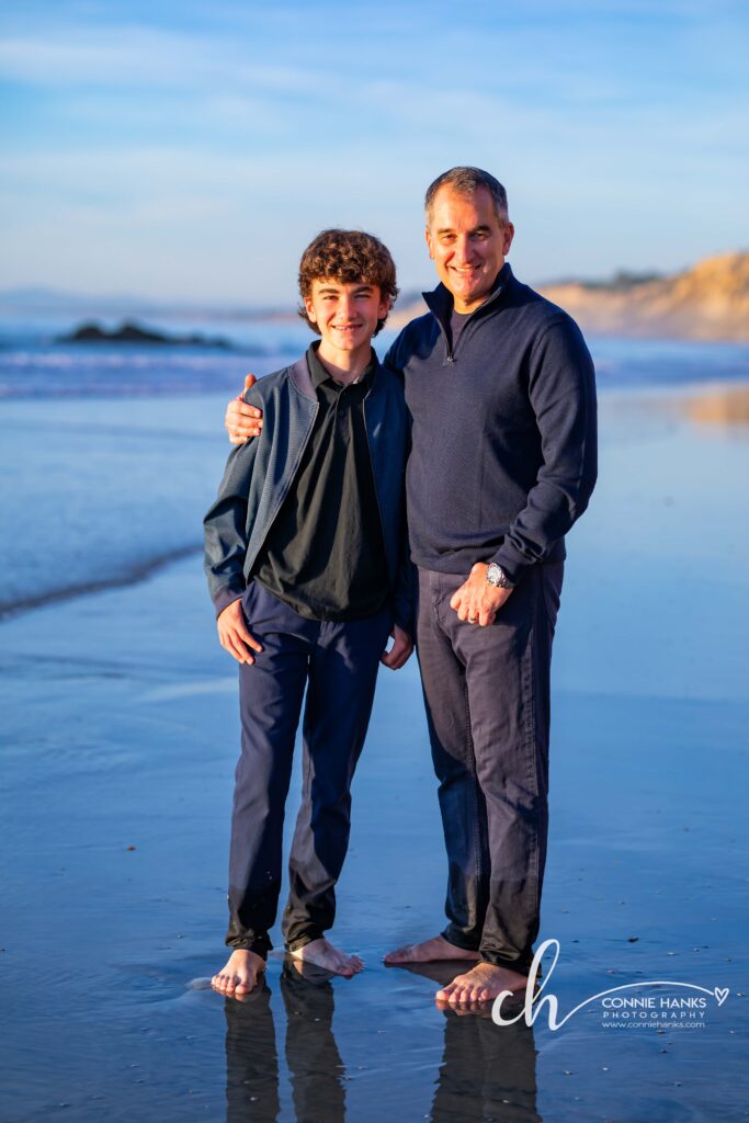 Family photos at Scripps Pier, La Jolla Beach. Stylized family with toes in sand at pier and cliffs.
