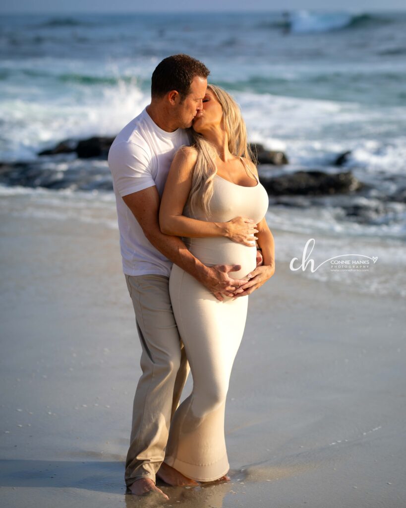 Maternity photos at Windansea Beach, La Jolla. Couple along beach with rocks and crashing waves.