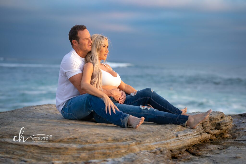 Maternity photos at Windansea Beach, La Jolla. Couple on cliffs along beach with watching sunset.