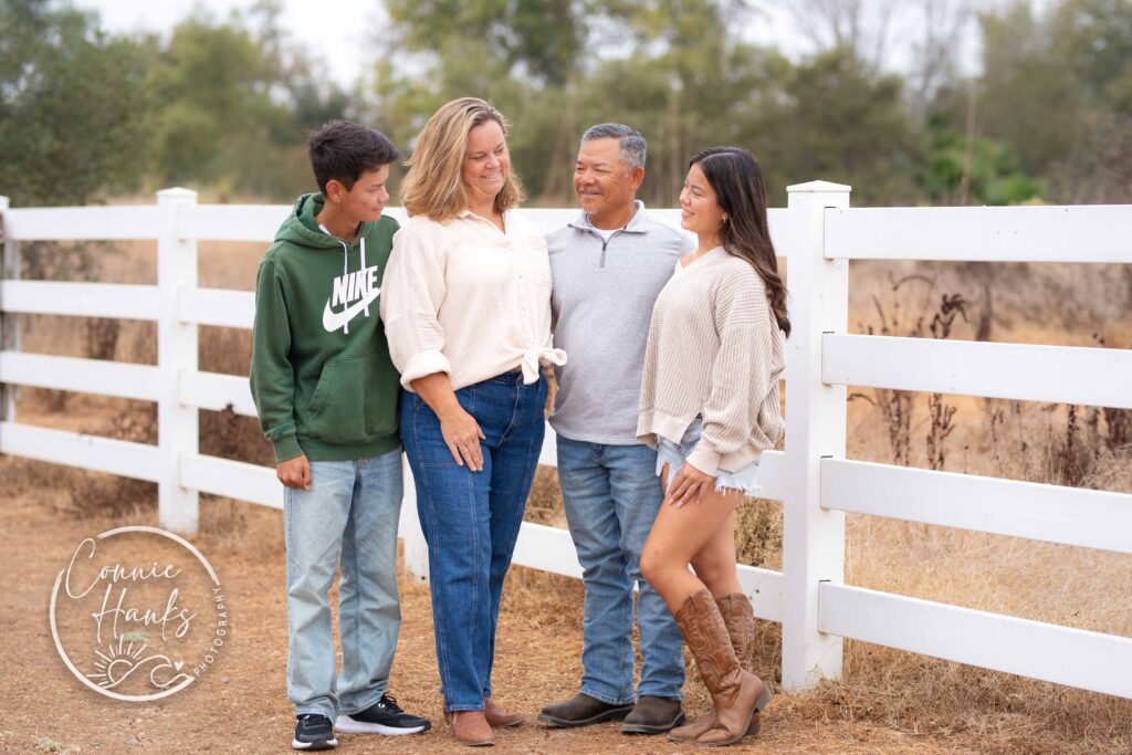 Family photos at Penasquitos Canyon, San Diego, California. Family with teens in wooded tree area, pepper trees, cactus garden, white fencing and rustic vibes.