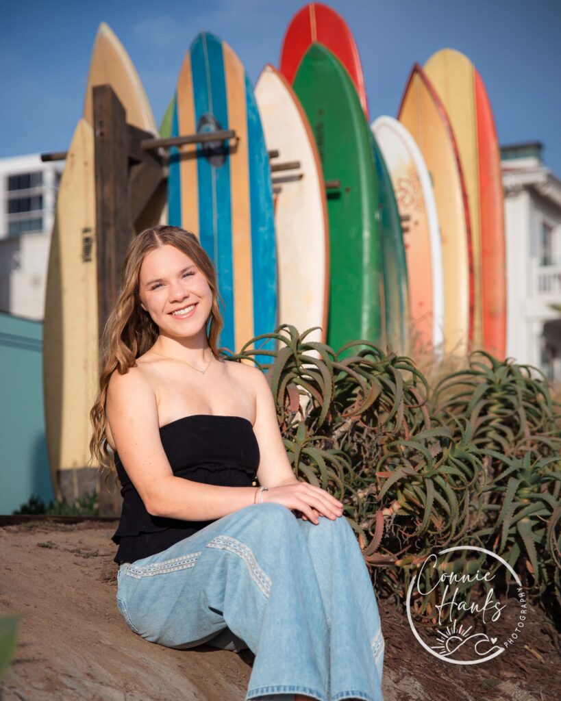 Senior photos at Coronado. Girl sitting with surfboards.