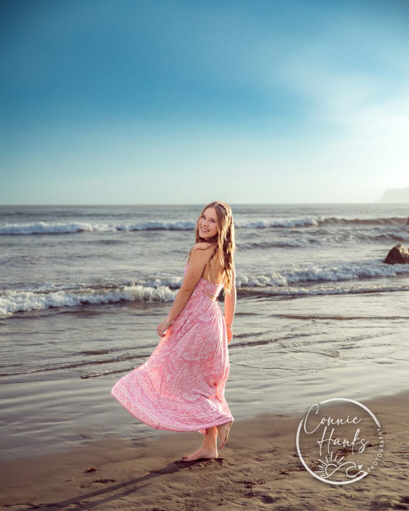 Senior photos at Coronado. Girl in pink dress at beach.